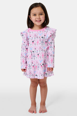 The Roller Rabbit Kids Monkey Pirouette Isa Dress features long sleeves, a pink collar, and ruffle shoulders. Crafted from soft Pima Cotton for all-day comfort, this dress showcases a playful pattern of cartoon monkeys dancing pirouettes on a white background.
