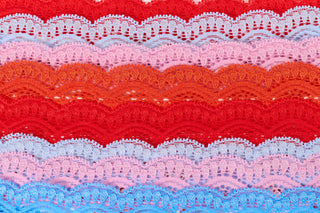 Roller Rabbit Print. Stack of colorful lace fabric swatches in red, pink, and blue.