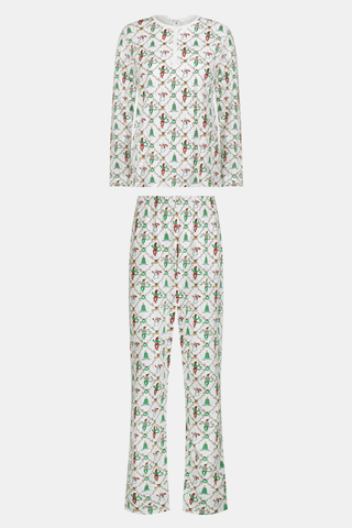 A woman wears a SERFLEX Deck The Halls Bailey Pajamas set featuring a short-sleeved top and shorts with a white background and a repeating Christmas-themed pattern of elves, snowmen, and evergreen trees.