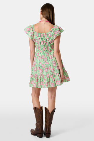 The Kids Verdant Floral Ryan Dress by Roller Rabbit is a green dress for little ones, showcasing pink and white hibiscus flowers in a floral block print. It features ruffled sleeves, a matching diaper cover, and is crafted from soft cotton for comfortable pullover wear.