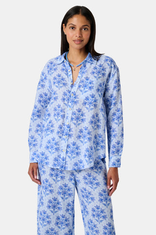 Close-up of the light blue Indigo Garden Paige Pant by Roller Rabbit, featuring a repeating pattern of darker blue floral designs and small star-like shapes. The fabric appears slightly wrinkled.