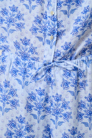 A woman stands against a plain light background wearing the Roller Rabbit Indigo Garden Boyfriend Shirt, a button-up long-sleeve pajama top in a blue floral print paired with matching wide-leg pants.