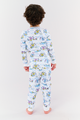 A young child with curly hair stands barefoot, facing away, wearing matching Kids April Showers Pajamas featuring colorful cartoon sea creatures printed on a white background.