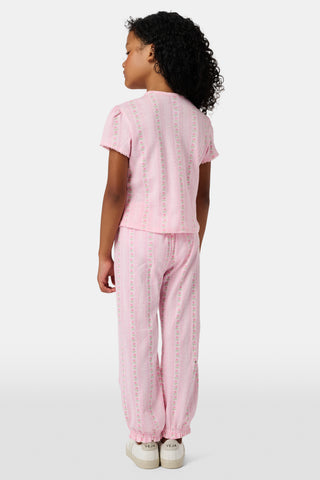 The Kids Daisy Heart Stripe Lucy Pants by Roller Rabbit are crafted from soft Pima cotton genie pant fabric in rose pink, featuring an elastic waistband and cuffs, with a subtle striped pattern and small floral designs throughout—making them a charming addition to girls' fashion.