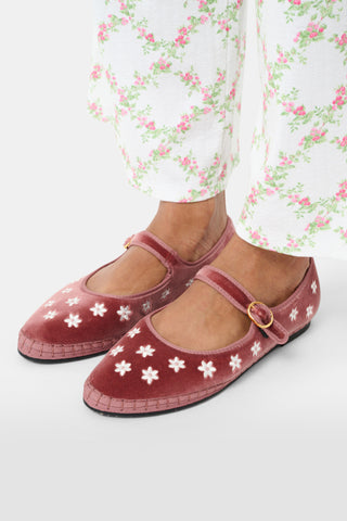Red floral shoes worn with white pants featuring pink flowers on a white background