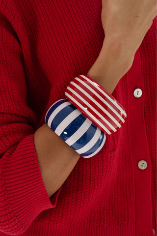 The Roller Rabbit Striped Bangle is a round, wide oversized bracelet featuring alternating vertical navy blue and white stripes, displayed on a plain light gray background.
