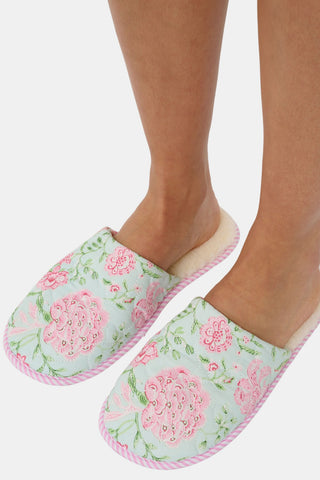 The Camellia Block Quilted Slippers by Roller Rabbit feature a cozy floral pink and green pattern, quilted detailing, a soft fuzzy lining, and pink striped trim around the sole.