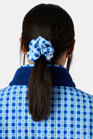 The Roller Rabbit Gingham Hearts Scrunchie Set Of 2 features one pink and white gingham scrunchie with small hearts and one blue and white gingham scrunchie with small hearts, displayed vertically on a plain background.
