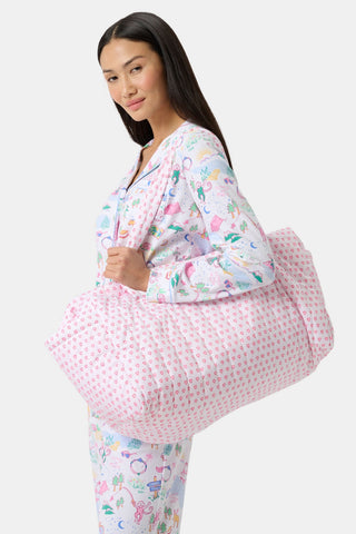 The Roller Rabbit Hearts Quilted Weekender is a rectangular pink and white travel bag with two handles, showcasing a pink heart pattern on quilted nylon, set against a plain light gray background.