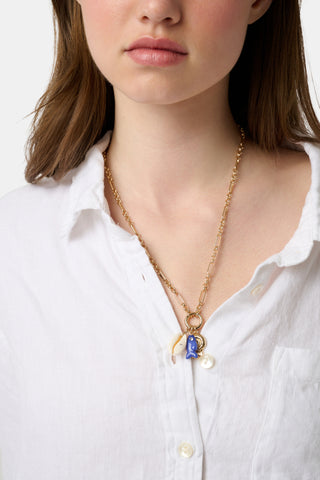 Roller Rabbit’s Coastal Charm Necklace features a gold-tone chain with three charms—a white seashell, blue fish, and gold spiral shell—capturing seaside style. Displayed on a plain white background, it's perfect for beach jewelry lovers.