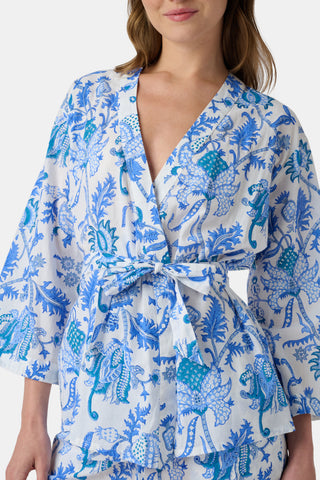 A woman poses barefoot against a plain white background wearing the Roller Rabbit Amanda Christy Set, a matching lounge set with a blue and white floral Amanda print, featuring a belted long-sleeve top and loose-fitting pants.