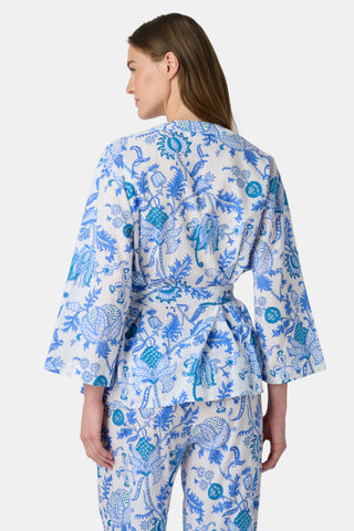 A woman poses barefoot against a plain white background wearing the Roller Rabbit Amanda Christy Set, a matching lounge set with a blue and white floral Amanda print, featuring a belted long-sleeve top and loose-fitting pants.