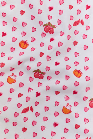 The Roller Rabbit Infant Autumn Hearts Zipper Footie is a white baby sleeper with long sleeves and footies, decorated with a charming pattern of small pink, red, and orange hearts and bears. Made from soft Pima cotton, these pajamas feature a convenient front diagonal zipper closure for easy dressing.