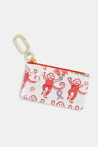 Introducing the Roller Rabbit Alpha Chi Omega Monkey Coin Pouch—a small zippered pouch featuring playful red monkeys, pink stars, and flowers on a white background. Crafted from durable cotton canvas with a protective poly coating for water-resistant convenience, it’s finished with a gold keychain clip for easy attachment.