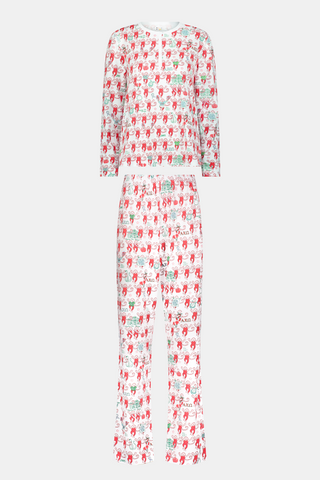 A woman stands outside with her arms crossed, wearing the Roller Rabbit Alpha Chi Omega Monkey Pajamas—a white Henley top and elastic waist pajama set featuring playful red and pink monkey patterns. She holds a matching quilted bag and carries a small heart-shaped blue and white polka dot purse.