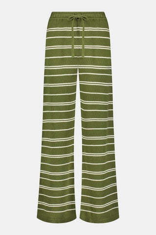 A person wearing the Roller Rabbit Autumn Stripe Olivia Pant—green and white striped, pull-on, flared—and a matching sweater lifts the hem to reveal their midriff. Brown slippers are visible. The background is white.