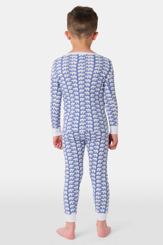 A girl wears Kids Hathi Pajamas—blue and white, full-length, long-sleeve onesie with a white elephant print and white cuffs, crafted from 100% Pima Cotton—smiling barefoot against a plain light background.