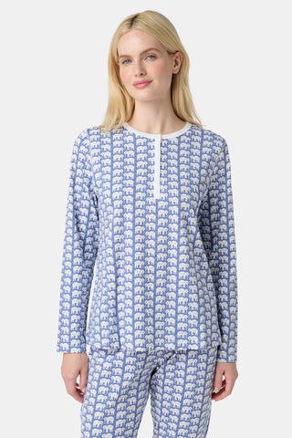 A woman stands barefoot in Roller Rabbit's Hathi Pajamas, a blue and white cotton set with a repeating elephant print, featuring a long-sleeve top and pants, against a plain white background.