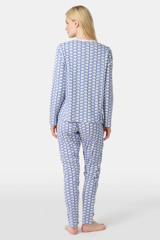 A woman stands barefoot in Roller Rabbit's Hathi Pajamas, a blue and white cotton set with a repeating elephant print, featuring a long-sleeve top and pants, against a plain white background.
