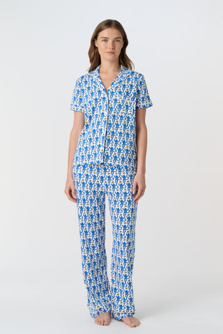 The Monkey Polo Pajamas feature a playful pattern of stylized blue monkeys with curly tails and yellow butterflies on white, arranged in alternating shades and directions—perfect for matching pajama sets.