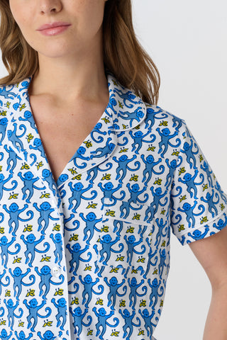 The Monkey Polo Pajamas feature a playful pattern of stylized blue monkeys with curly tails and yellow butterflies on white, arranged in alternating shades and directions—perfect for matching pajama sets.