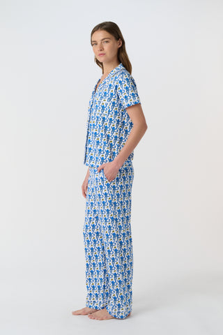 The Monkey Polo Pajamas feature a playful pattern of stylized blue monkeys with curly tails and yellow butterflies on white, arranged in alternating shades and directions—perfect for matching pajama sets.