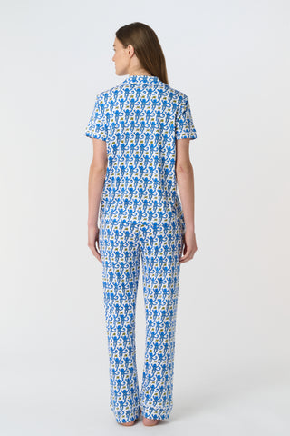 The Monkey Polo Pajamas feature a playful pattern of stylized blue monkeys with curly tails and yellow butterflies on white, arranged in alternating shades and directions—perfect for matching pajama sets.