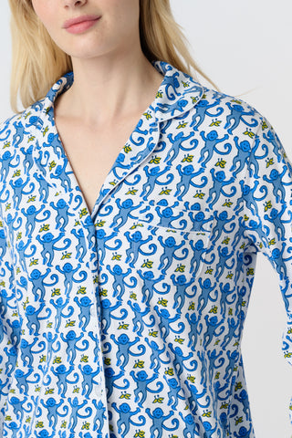 A person with long blonde hair wears Roller Rabbit Monkey Long Sleeve Polo Pajamas in blue and white Pima cotton, standing barefoot on a white background.