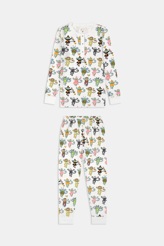 A smiling child in Roller Rabbit’s Kids Boo Crew Pajamas, crafted from soft Pima cotton, sits with arms raised on outdoor steps among women in coordinating patterned pajamas, all sharing a cheerful and relaxed moment together.
