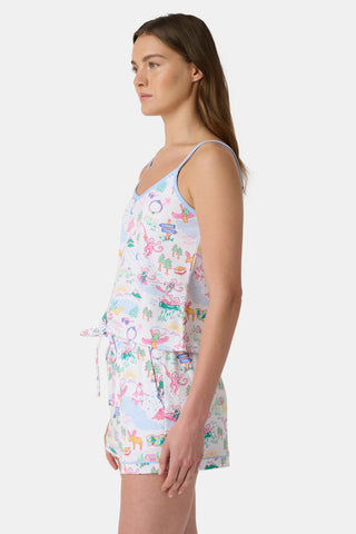 A woman stands barefoot in the Roller Rabbit Camp RR Mischa Set, a whimsical animal and floral print two-piece loungewear with a sleeveless V-neck tank with blue straps and matching drawstring waist shorts.