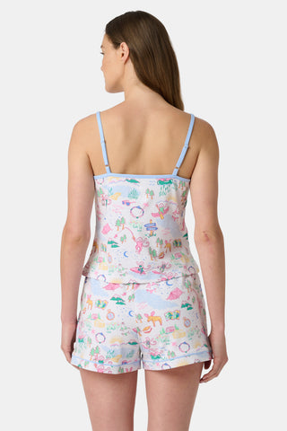 A woman stands barefoot in the Roller Rabbit Camp RR Mischa Set, a whimsical animal and floral print two-piece loungewear with a sleeveless V-neck tank with blue straps and matching drawstring waist shorts.