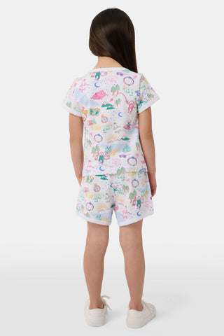 A young girl with long brown hair wears the Roller Rabbit Kids Camp RR Playa Play Set, a 100 Pima Cotton two-piece featuring colorful prints of unicorns, tents, deer, and trees. She faces forward against a plain light background.