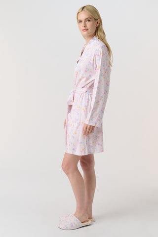 A woman with blonde hair models the Roller Rabbit Candy Heart Stripe Blake Robe—a light pink, knee-length Pima cotton robe with candy heart stripes and a waist tie—against a plain white background.