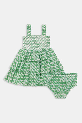 The Kids Cane Kenia Dress by Roller Rabbit is a green and white sleeveless cotton summer dress with a smocked bodice, ruffled skirt, matching diaper cover, and all-over leaf pattern. Shown on a plain white background.