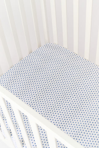 A white Hearts Crib Sheet by Roller Rabbit, featuring a repeating pattern of small, blue, hand-drawn heart shapes arranged in neat diagonal rows—an adorable choice for baby bedding.