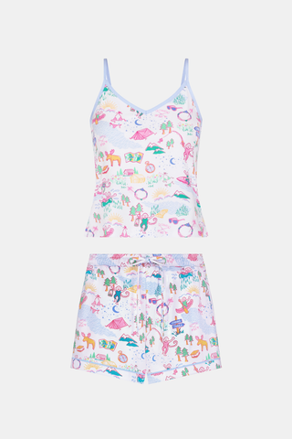 A woman stands barefoot in the Roller Rabbit Camp RR Mischa Set, a whimsical animal and floral print two-piece loungewear with a sleeveless V-neck tank with blue straps and matching drawstring waist shorts.