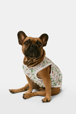 A woman wears a SERFLEX Deck The Halls Bailey Pajamas set featuring a short-sleeved top and shorts with a white background and a repeating Christmas-themed pattern of elves, snowmen, and evergreen trees.