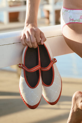 The Jena Embroidery Pierre by FLABELUS is a beige linen Mary Jane shoe with white embroidery, red trim and strap, gold button, and red sole. Made in Spain. Displayed on a plain white background.
