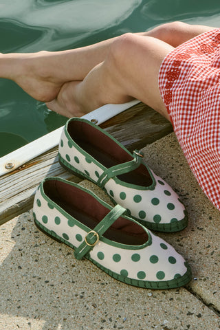 The FLABELUS Polka Dot Pierre is a cream Mary Jane flat with green trim, a green strap featuring a gold buckle, and polka dots—part of the Flabelus collaboration.