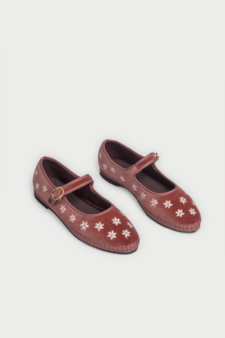 Red floral shoes worn with white pants featuring pink flowers on a white background