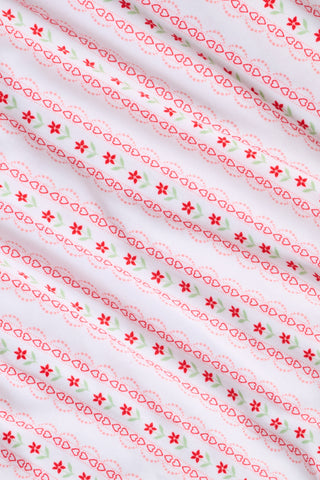 A woman smiles while wearing the Roller Rabbit Daisy Heart Stripe Jessie Long Sleeve Tee, a soft Pima cotton top adorned with pink and red daisies, paired with matching pajama bottoms, against a plain white background.