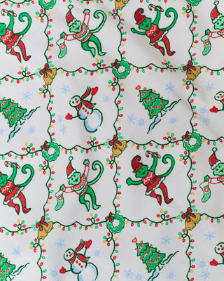 SERFLEX Infant Deck The Halls Foldover Footie in white featuring an all-over holiday pattern of monkeys, snowmen, and Christmas trees connected by string lights.