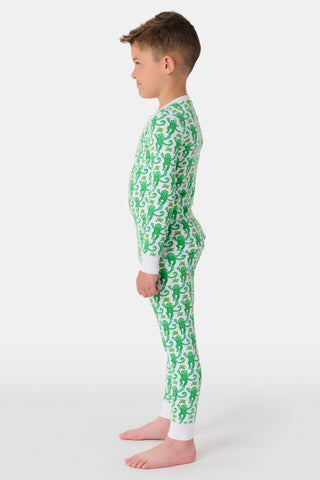 A young boy smiles at the camera, barefoot in Roller Rabbit’s Kids Monkey Pajamas— a matching top and bottom set featuring playful monkey prints and white cuffs, made from 100 pima cotton, against a plain white background.