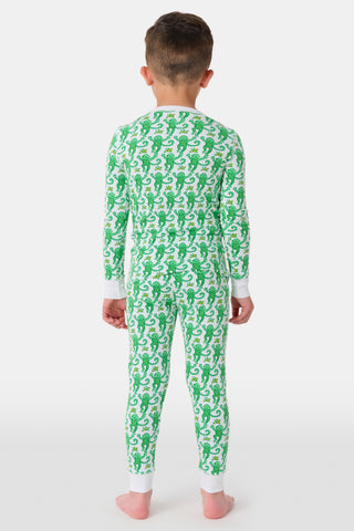 A young boy smiles at the camera, barefoot in Roller Rabbit’s Kids Monkey Pajamas— a matching top and bottom set featuring playful monkey prints and white cuffs, made from 100 pima cotton, against a plain white background.