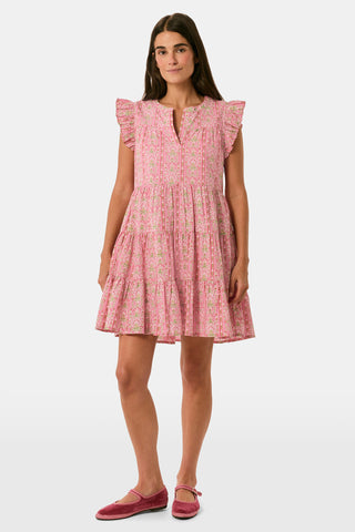 A woman models the Cora Floral Stripe Arles Top by Roller Rabbit—a loose, long-sleeved tunic in autumnal pink featuring a floral stripe block print and pintuck pleats on the chest—paired with white pants, against a plain light background.
