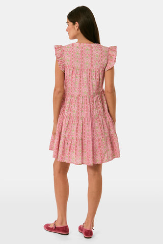 A woman models the Cora Floral Stripe Arles Top by Roller Rabbit—a loose, long-sleeved tunic in autumnal pink featuring a floral stripe block print and pintuck pleats on the chest—paired with white pants, against a plain light background.