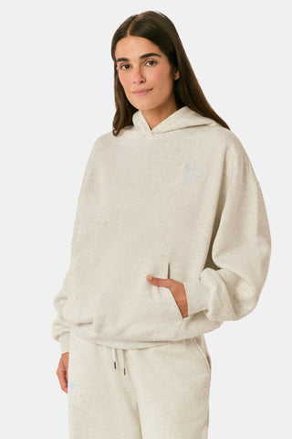 A person with long blonde hair wears the Roller Rabbit Sleep Club Lola Hoodie and wide leg sweatpants in light gray Dream Fleece, standing with hands in the hoodie pockets against a plain white background.