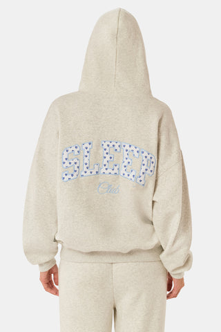 A person with long blonde hair wears the Roller Rabbit Sleep Club Lola Hoodie and wide leg sweatpants in light gray Dream Fleece, standing with hands in the hoodie pockets against a plain white background.