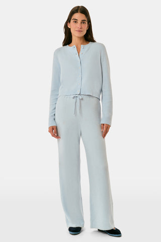 A woman poses with her arms crossed, wearing an icy blue AFFINA Moxie Cardigan with pearl-like buttons and matching drawstring pants.