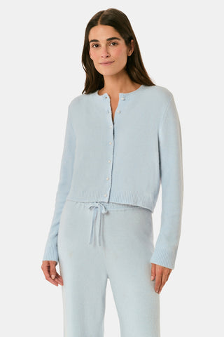 A woman poses with her arms crossed, wearing an icy blue AFFINA Moxie Cardigan with pearl-like buttons and matching drawstring pants.